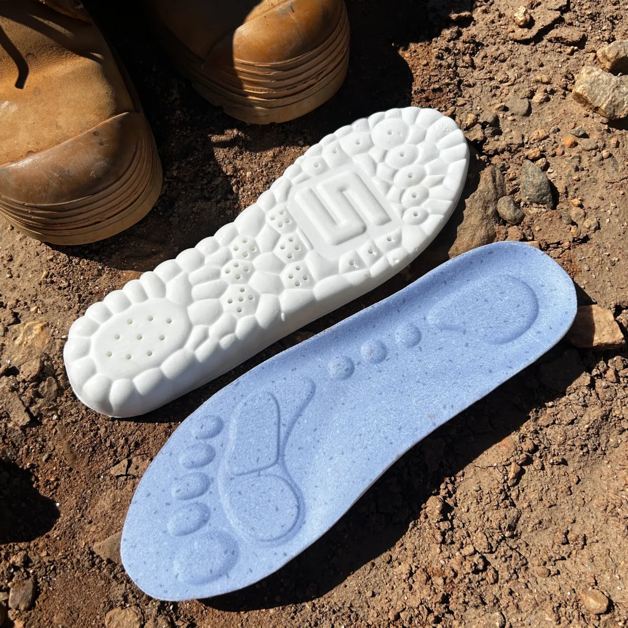 Work boots beside WorkFit insoles on a job site